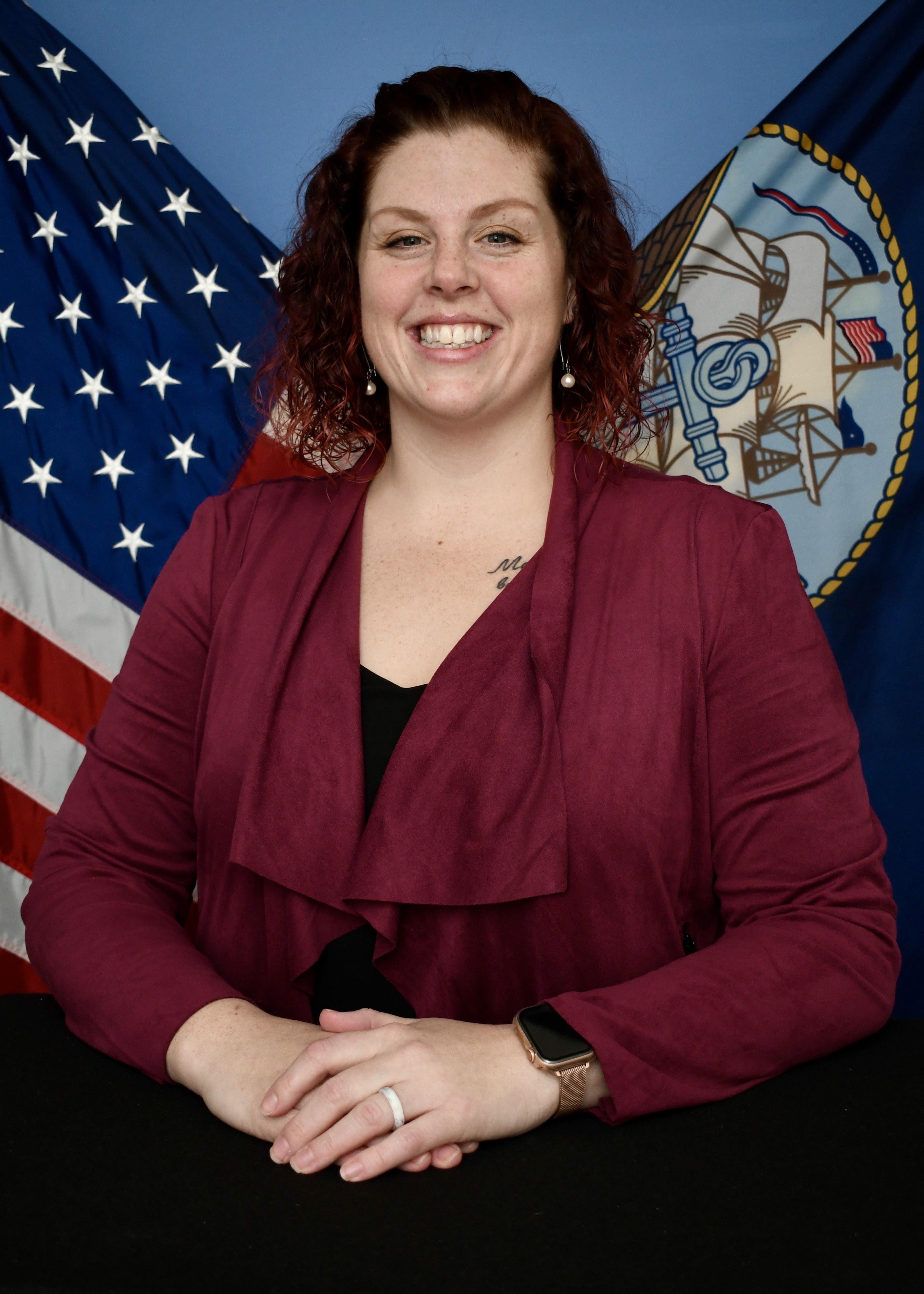 A picture of Kayla Favara in front of American and Navy flags