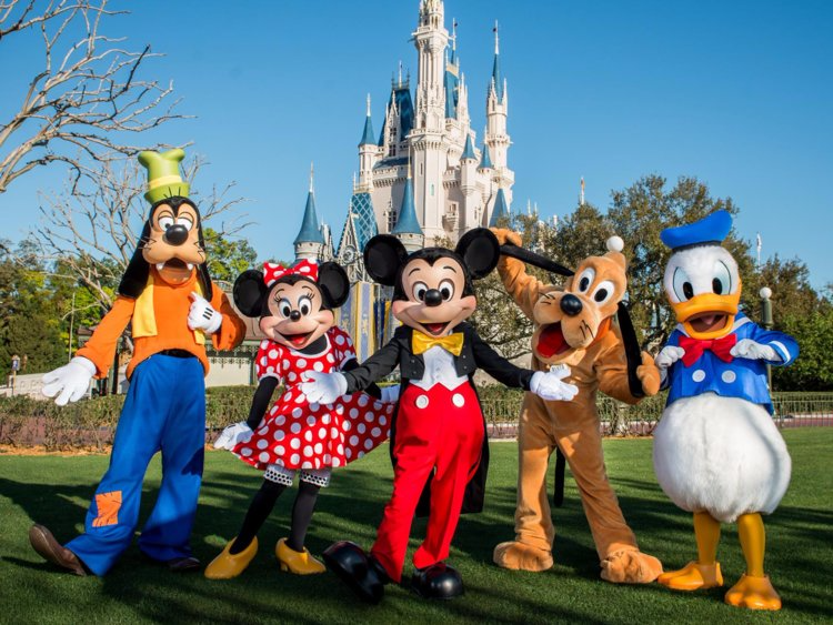 A picture of Disney costumed characters posing in front of Cinderella's Castle at Walt Disney World